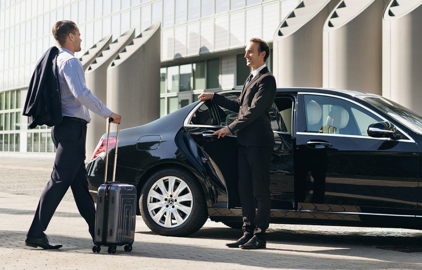 Chauffeur ouvrant la porte pour un passager devant un terminal